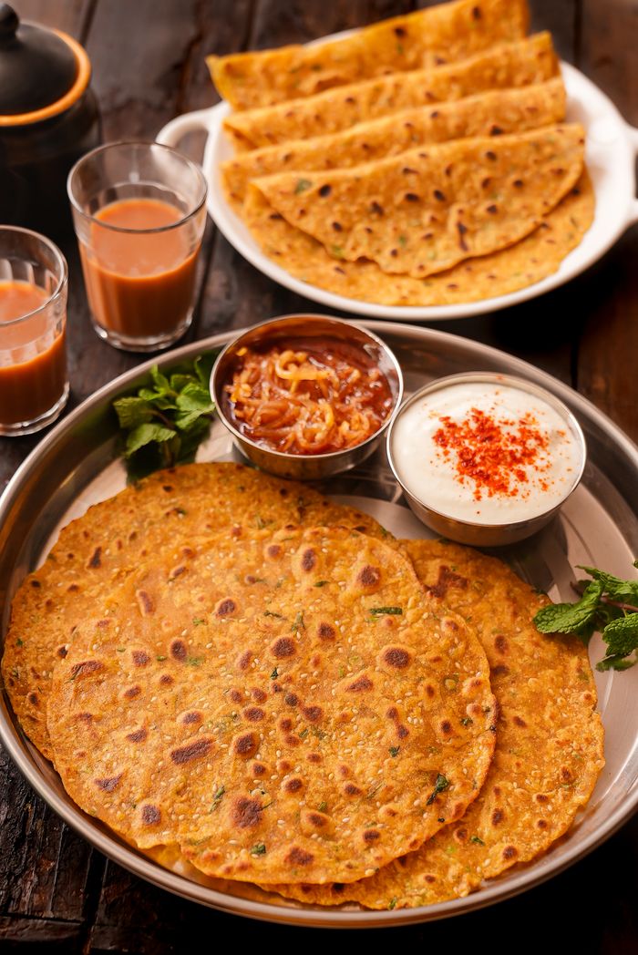 Indian paratha served with chutneys and masala chai, perfect for a hearty meal.