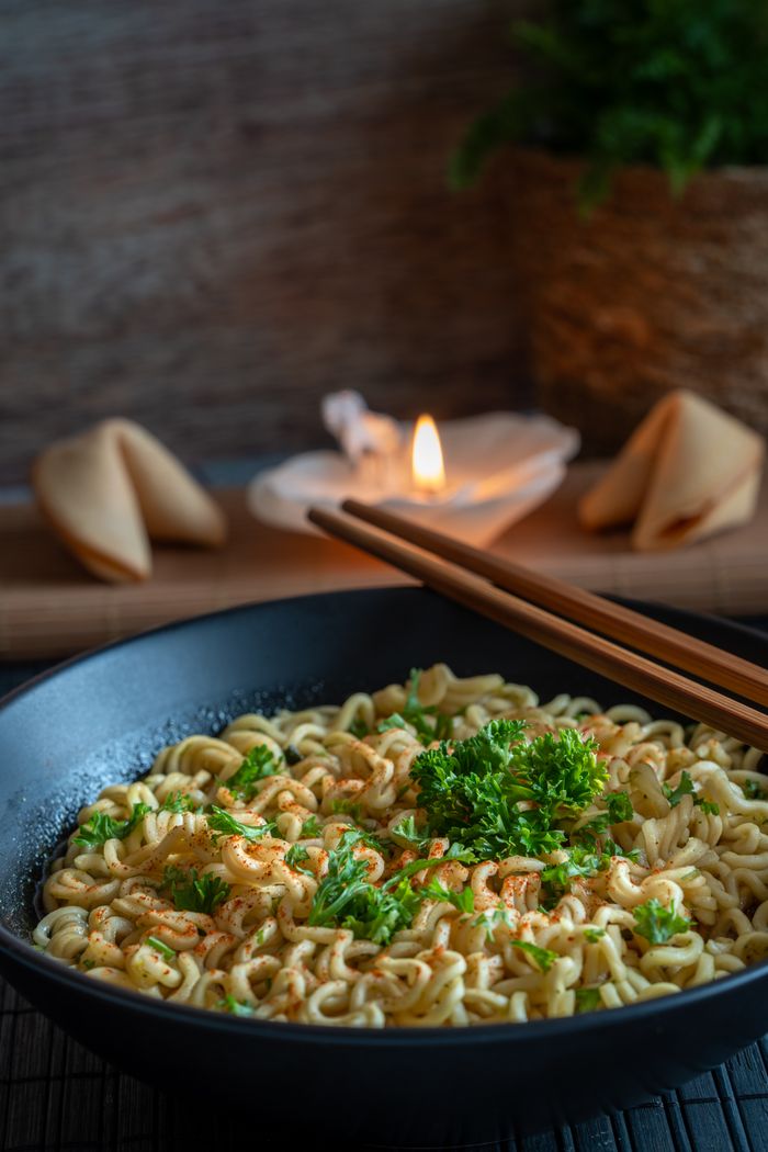 Warm ramen noodles with coriander, paired with fortune cookies and elegant chopsticks.