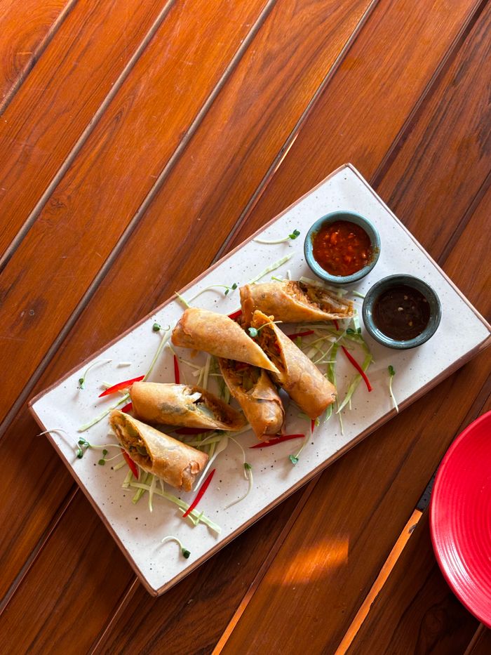 Appetizing spring rolls served with spicy sauces on a wooden table setting.